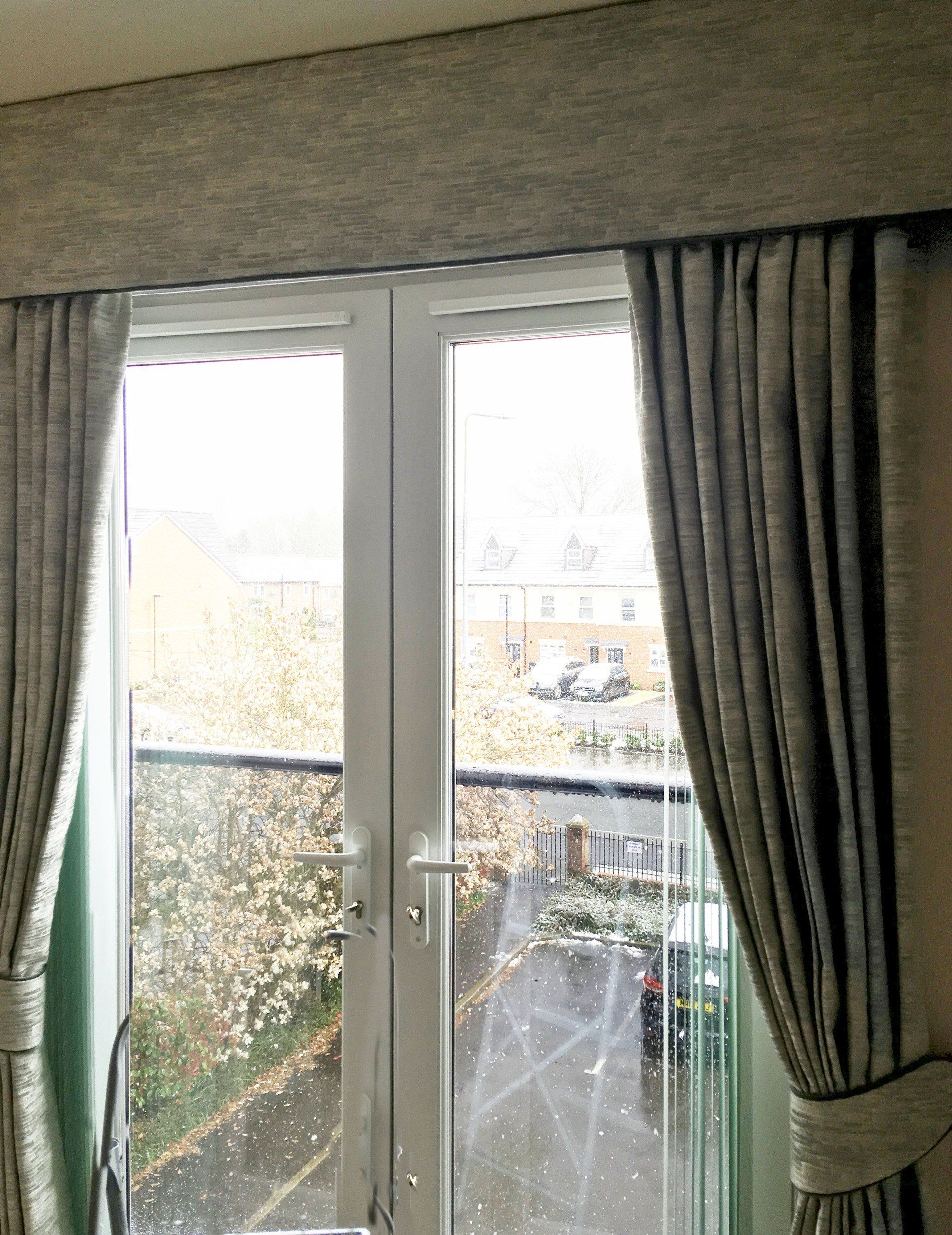 A room with a large window and curtains on it