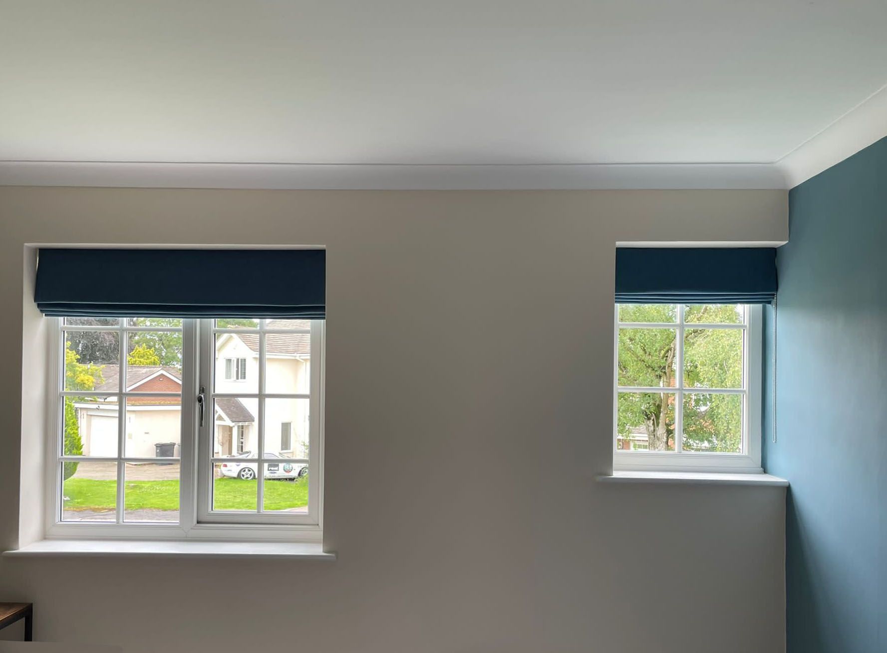 Two windows with blue blinds in a room with a blue wall.