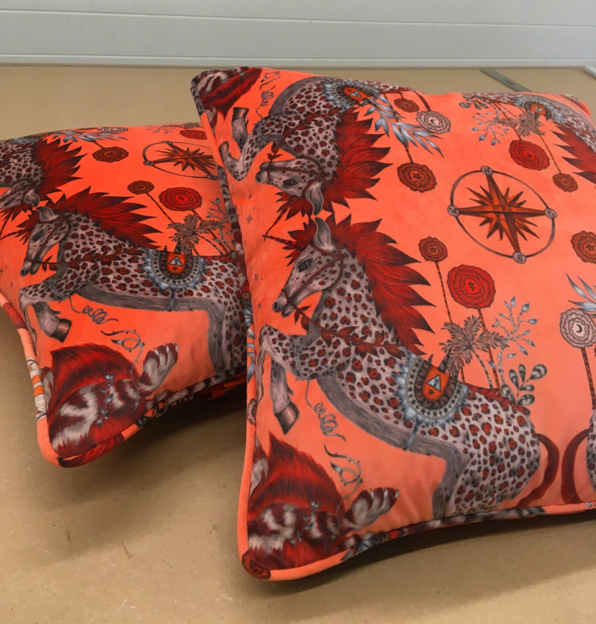 A pair of orange pillows with animals on them