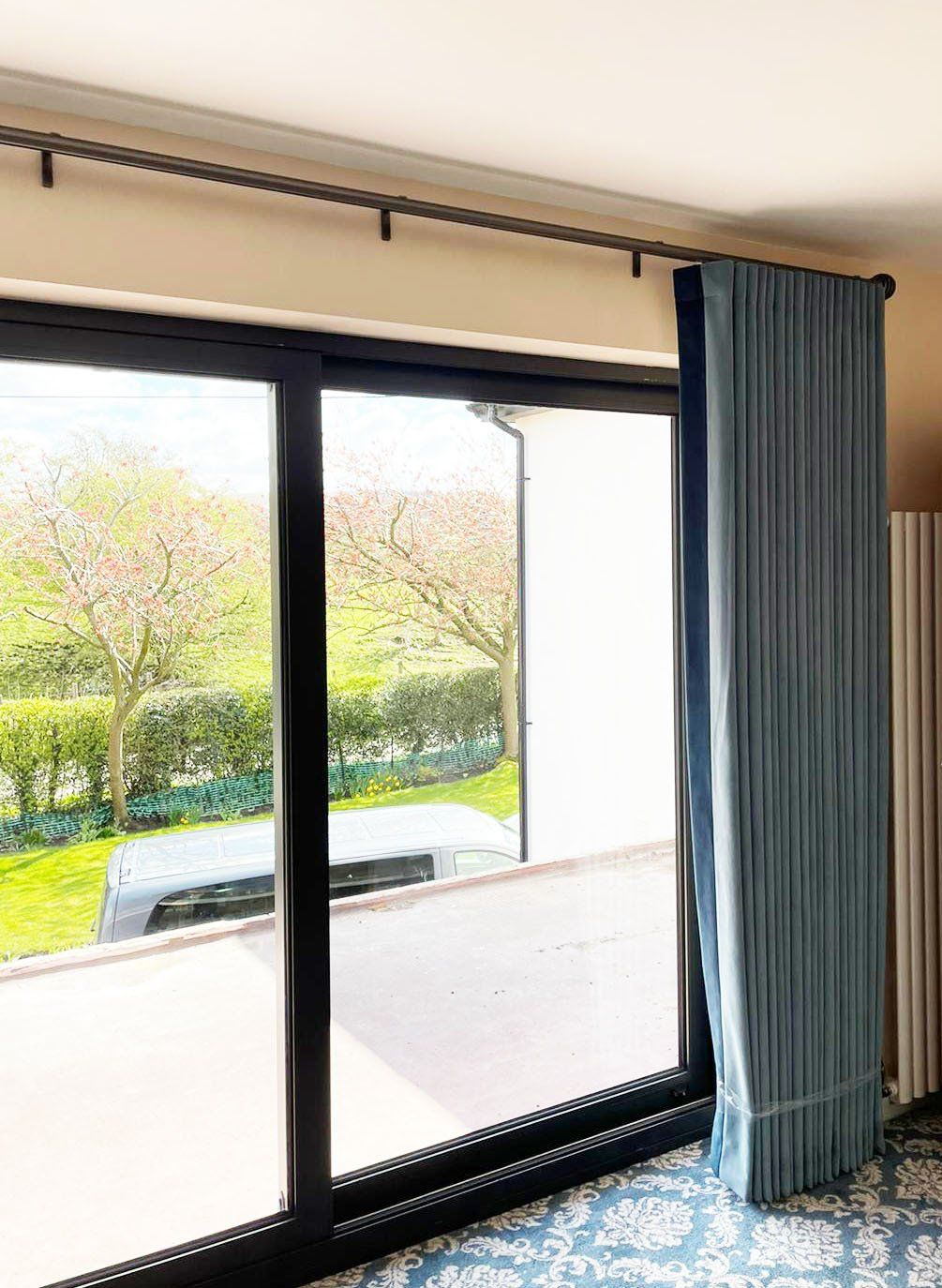 A room with a sliding glass door and blue curtains.