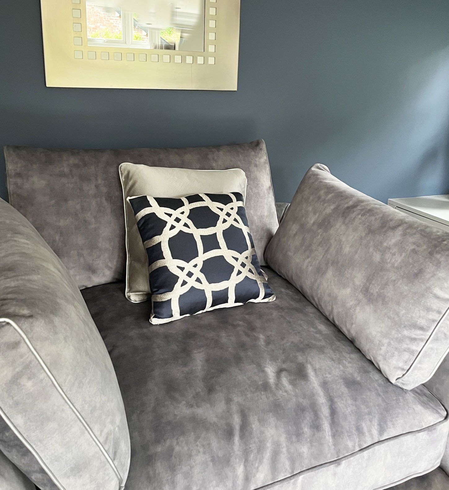A grey couch with a black and white pillow on it