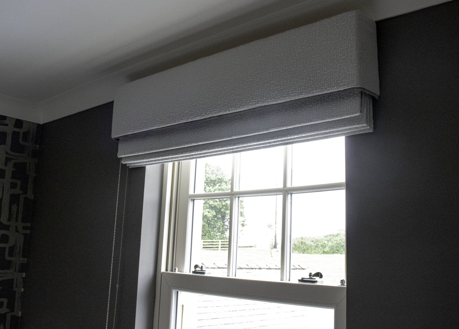 A window with a white texture roman blind on it with a matching pelmet