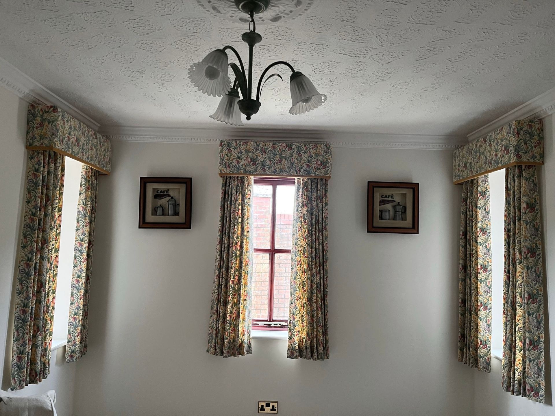 A room with a window , curtains and a chandelier.