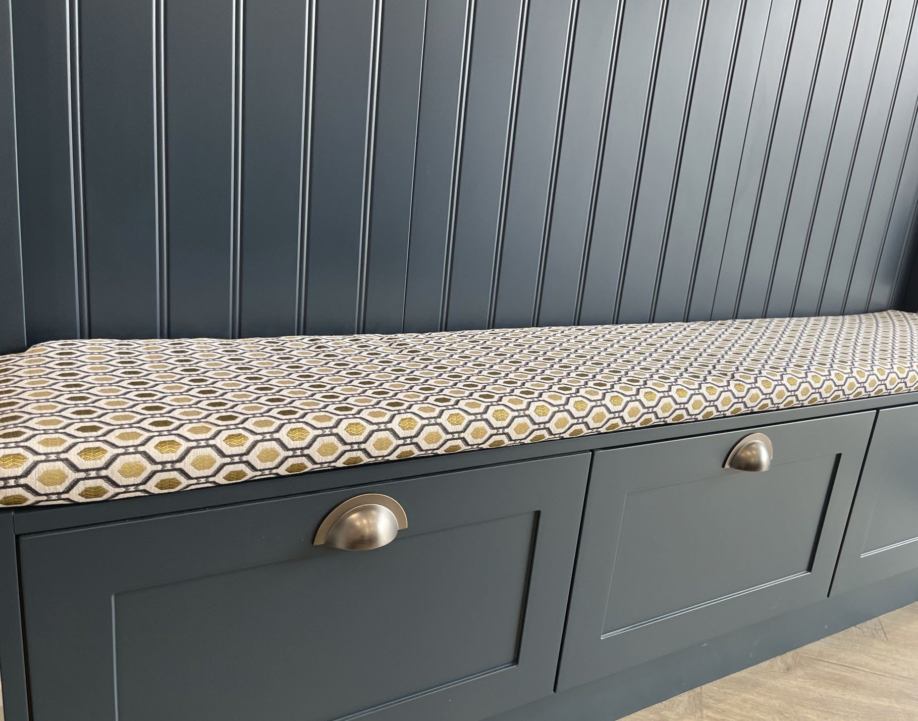 A bench with drawers underneath it and a cushion on top of it.