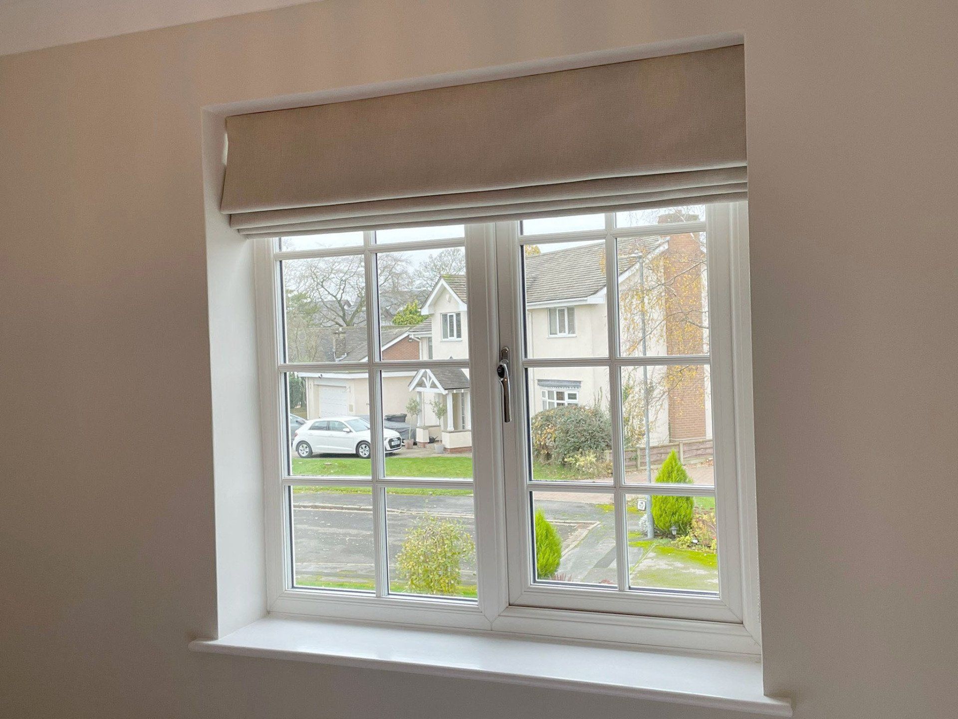 There is a window with a blind on it and a view of a house.