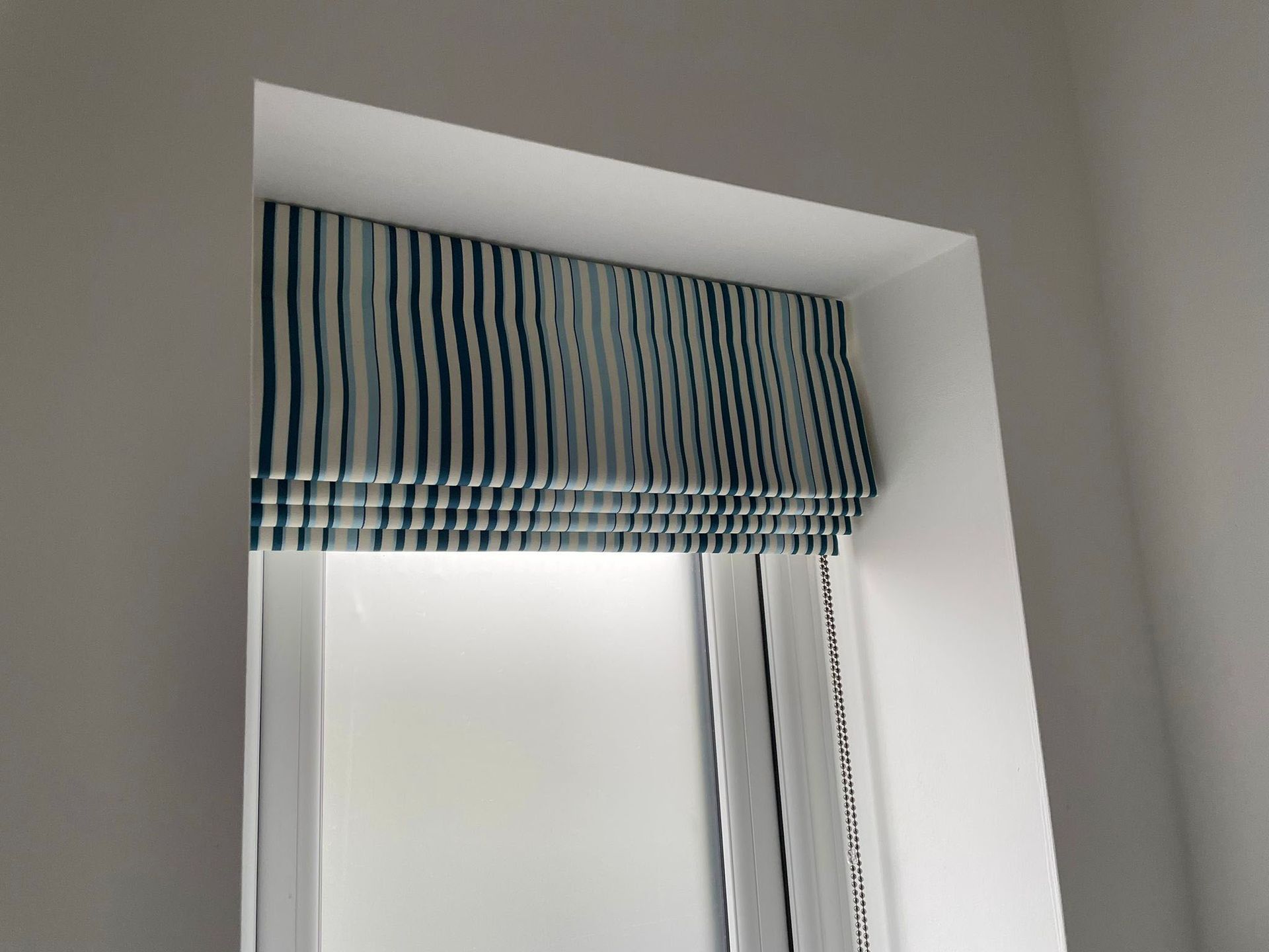 A window with a blue and white striped blind on it.