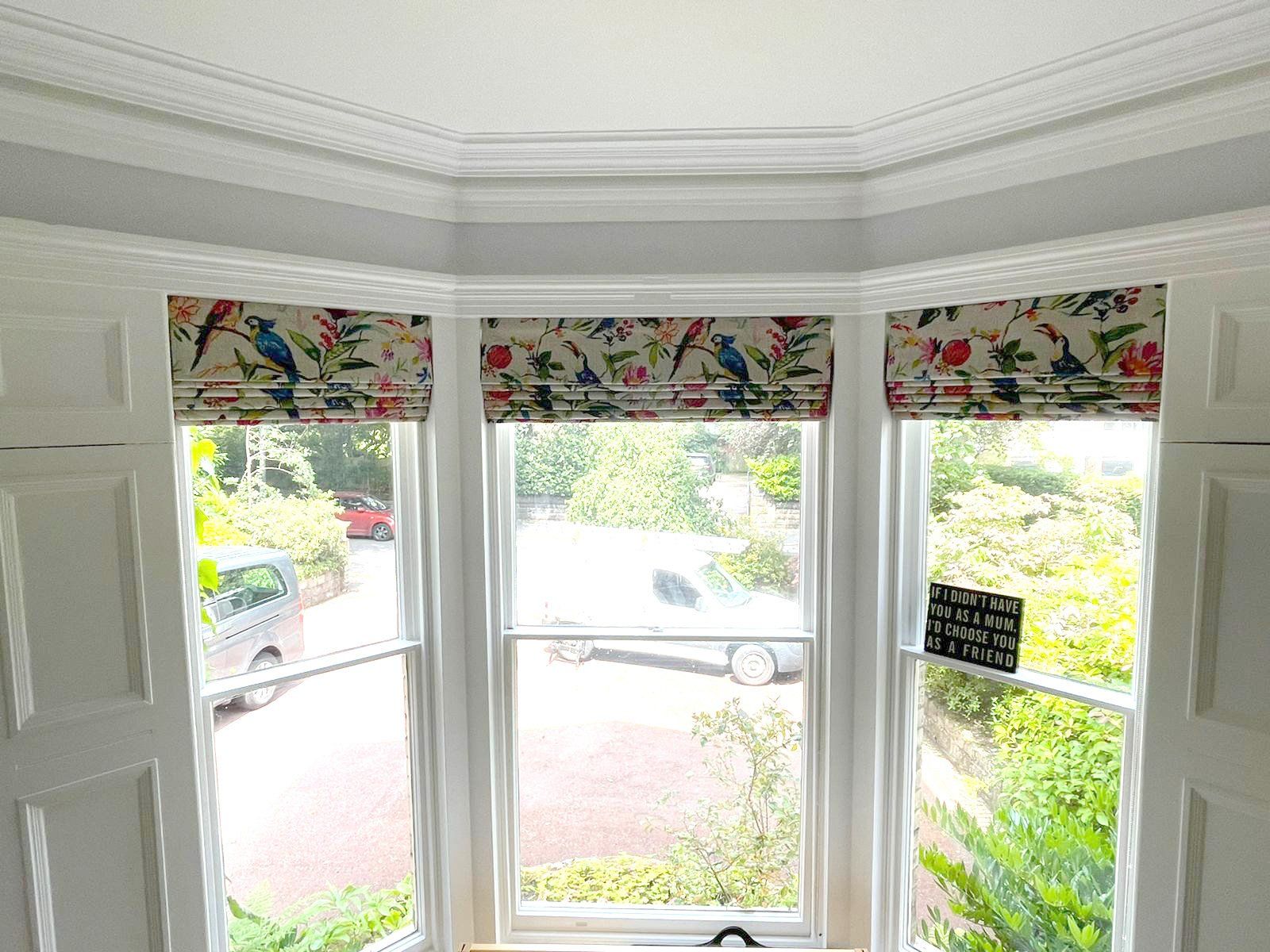 A bay window with roman blinds in a living room.