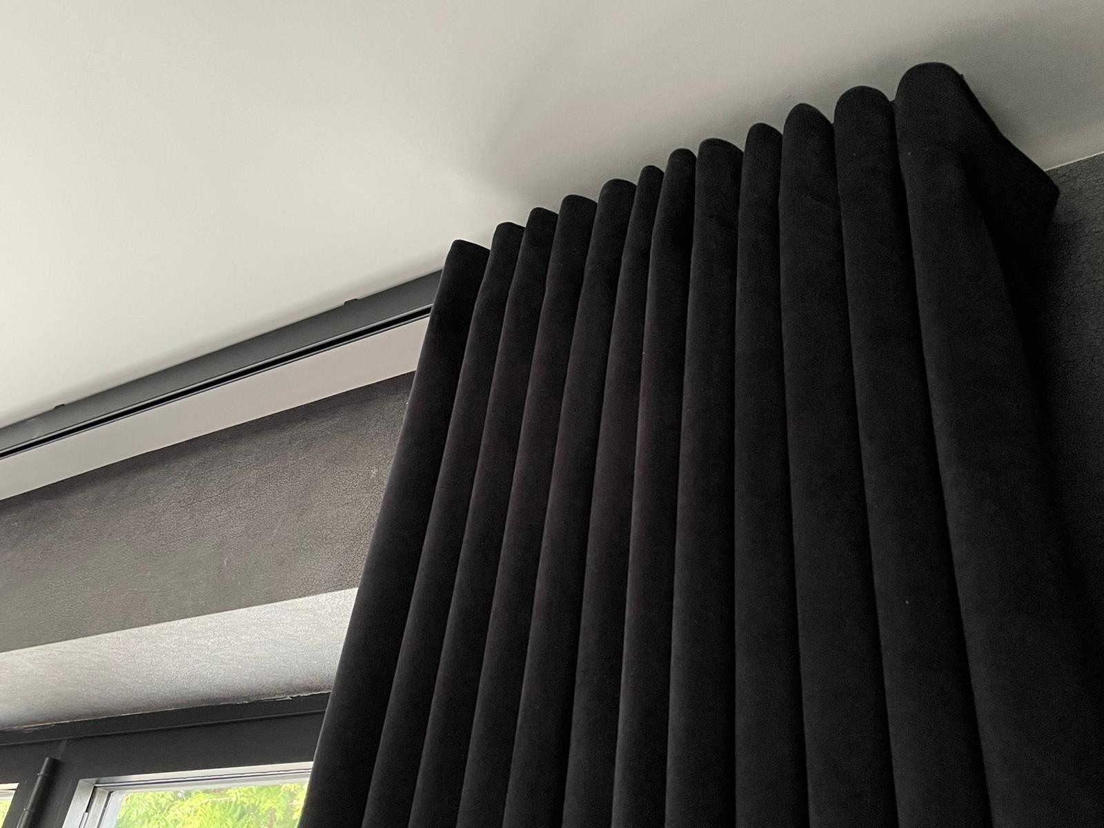 A close up of a pair of black curtains hanging from the ceiling.