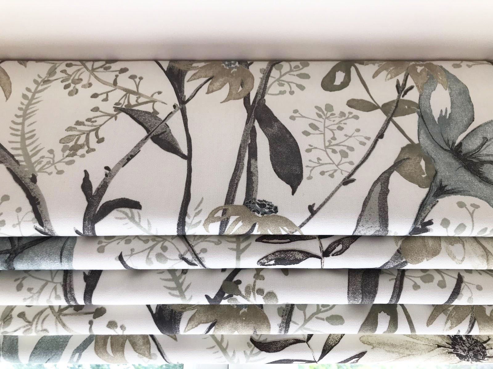 A close up of a roman shade with a floral pattern on it.