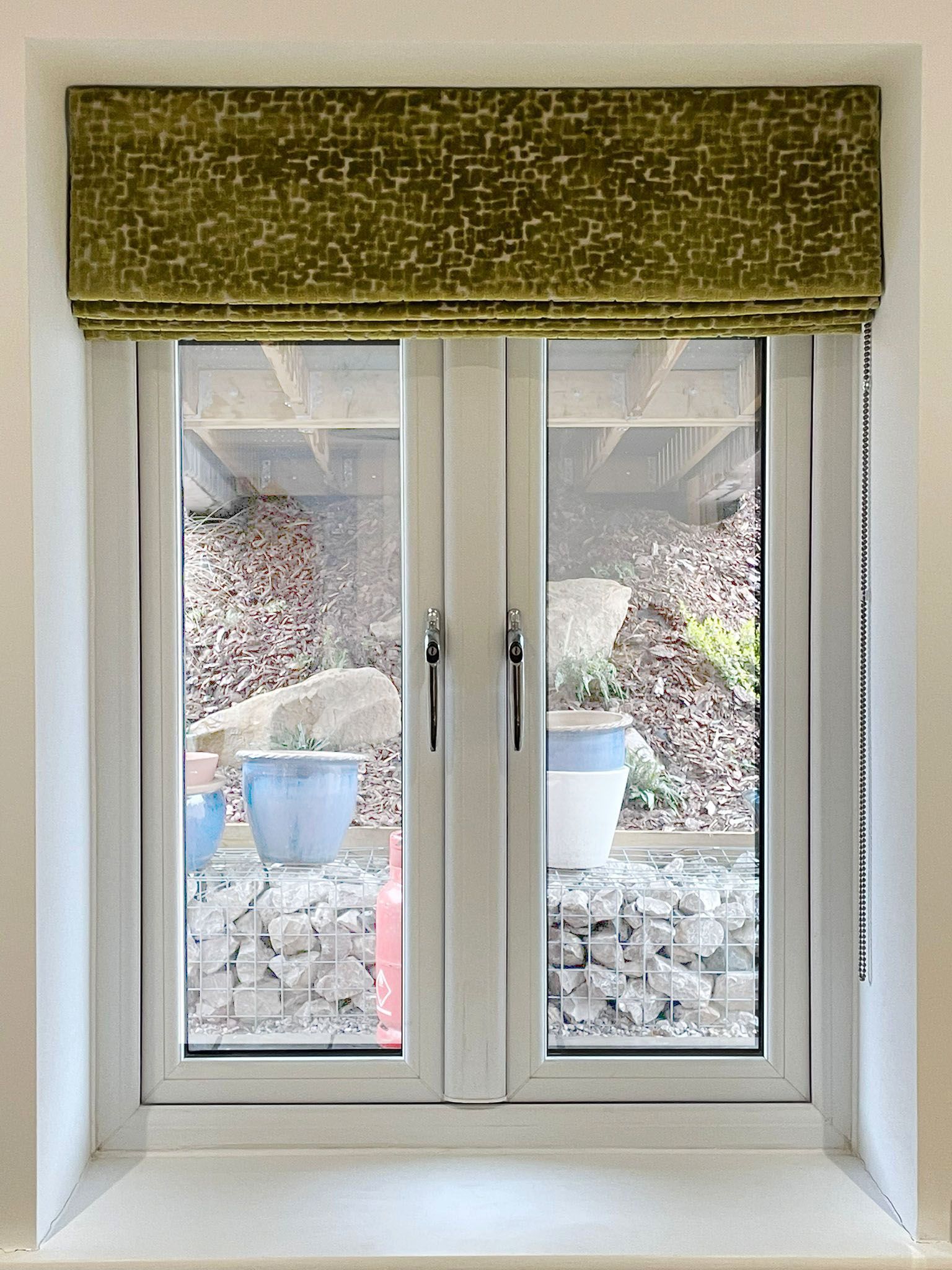 A white window with a green roman shade on it.