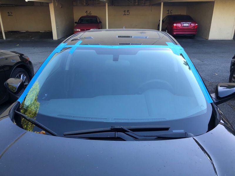 Black car with blue tape on windshield