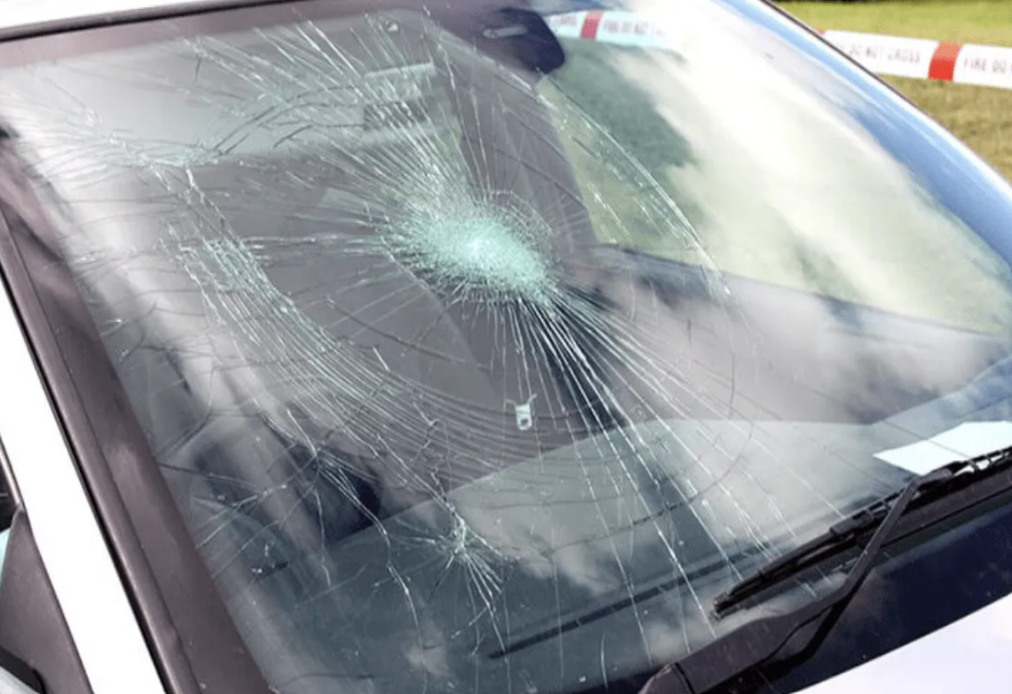 Cracked car windshield with a central impact point and radiating cracks.