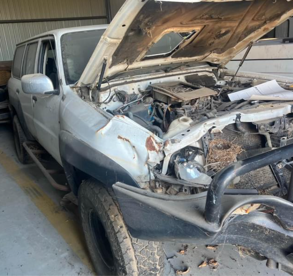 White damaged SUV parked in a storage space with its hood open. The front end has significant damage.  — Panel Pro Smash Repairs in Wodonga, VIC