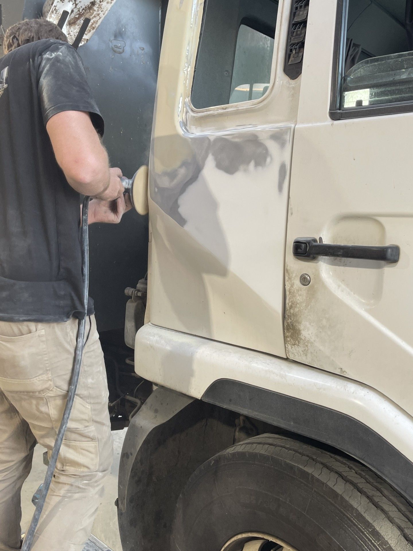 A person in a shop sands a beige truck door. They wear a black shirt and tan pants — Panel Pro Smash Repairs in Wodonga, VIC