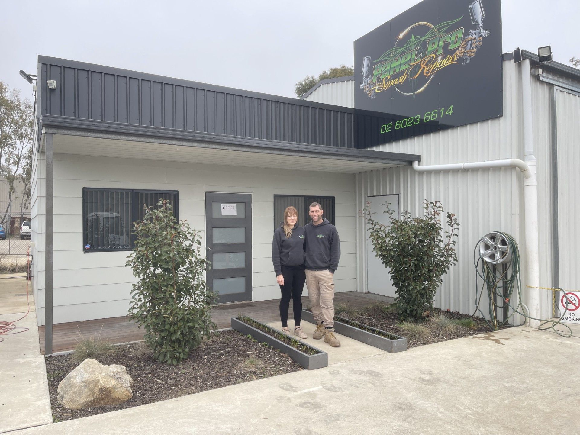 a couple stand in front of a bodywork shop — Panel Pro Smash Repairs in Wodonga, VIC