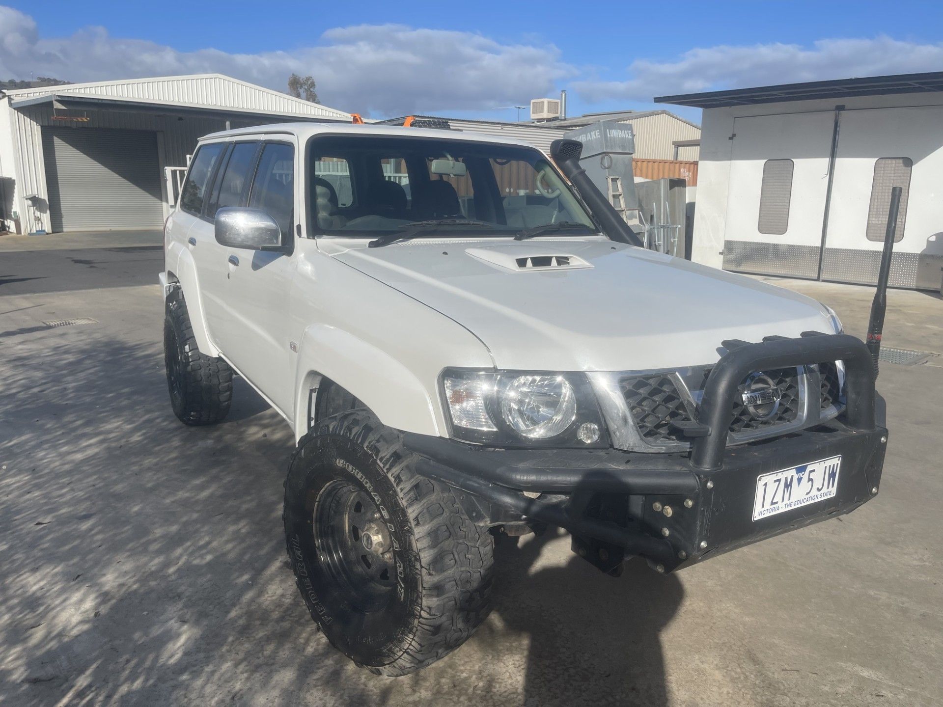 White SUV with large tires and a bull bar, parked outside a building on a sunny day — Panel Pro Smash Repairs in Wodonga, VIC