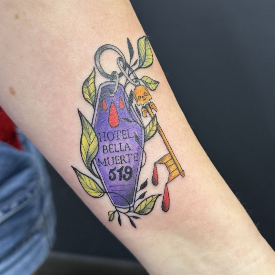 Tattoo of a purple Hotel Bella Muerte key tag with a dripping key, surrounded by green leaves. — Whitsunday Tattooing Airlie Beach in Whitsundays, QLD