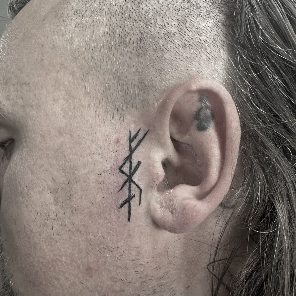 Man's face with a tattoo of Nordic runes on the cheek, near the ear. — Whitsunday Tattooing Airlie Beach in Whitsundays, QLD
