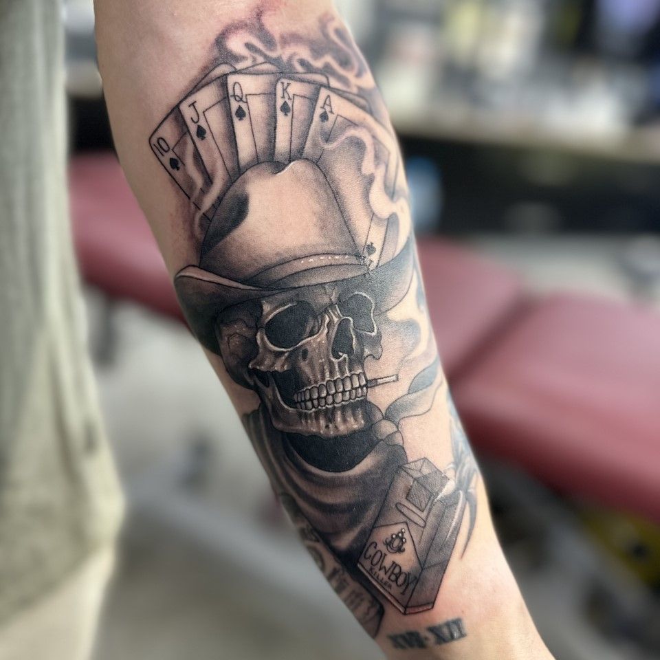 Tattoo of a skull in a cowboy hat smoking a cigarette, with playing cards and smoke. — Whitsunday Tattooing Airlie Beach in Whitsundays, QLD