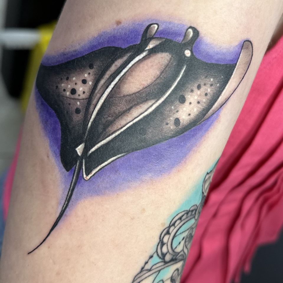 Black and white manta ray tattoo on arm with purple gradient background. — Whitsunday Tattooing Airlie Beach in Whitsundays, QLD