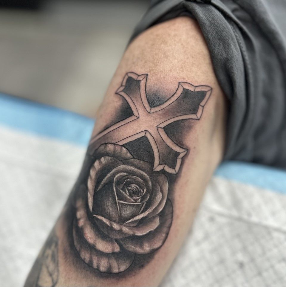 Black and gray tattoo of a cross over a rose on an arm. — Whitsunday Tattooing Airlie Beach in Whitsundays, QLD