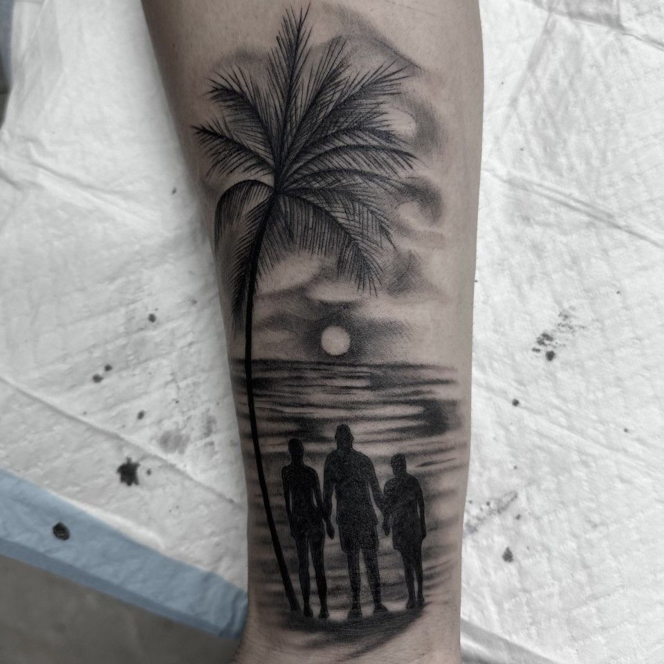 Black and white tattoo of a beach scene: palm tree, moon, figures silhouetted on shore. — Whitsunday Tattooing Airlie Beach in Whitsundays, QLD