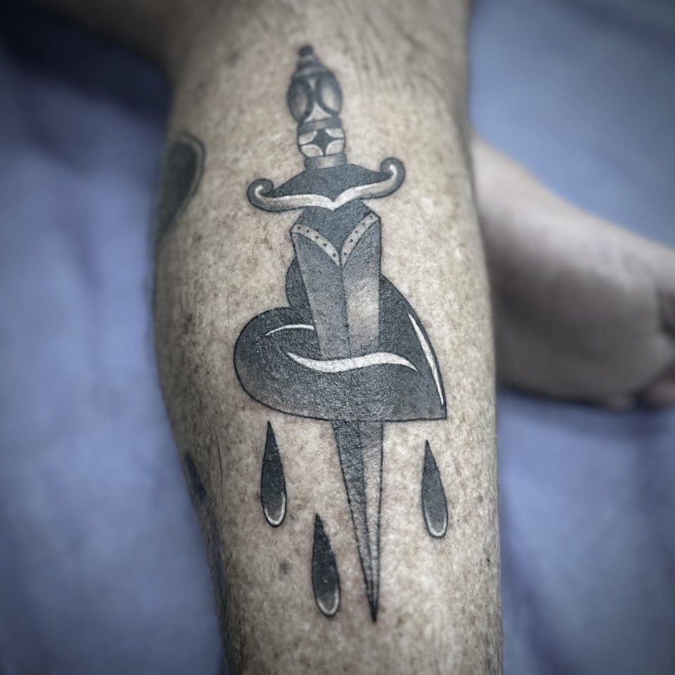 Tattoo of a dagger through a heart, with three teardrops, on a leg. Black and white. — Whitsunday Tattooing Airlie Beach in Whitsundays, QLD