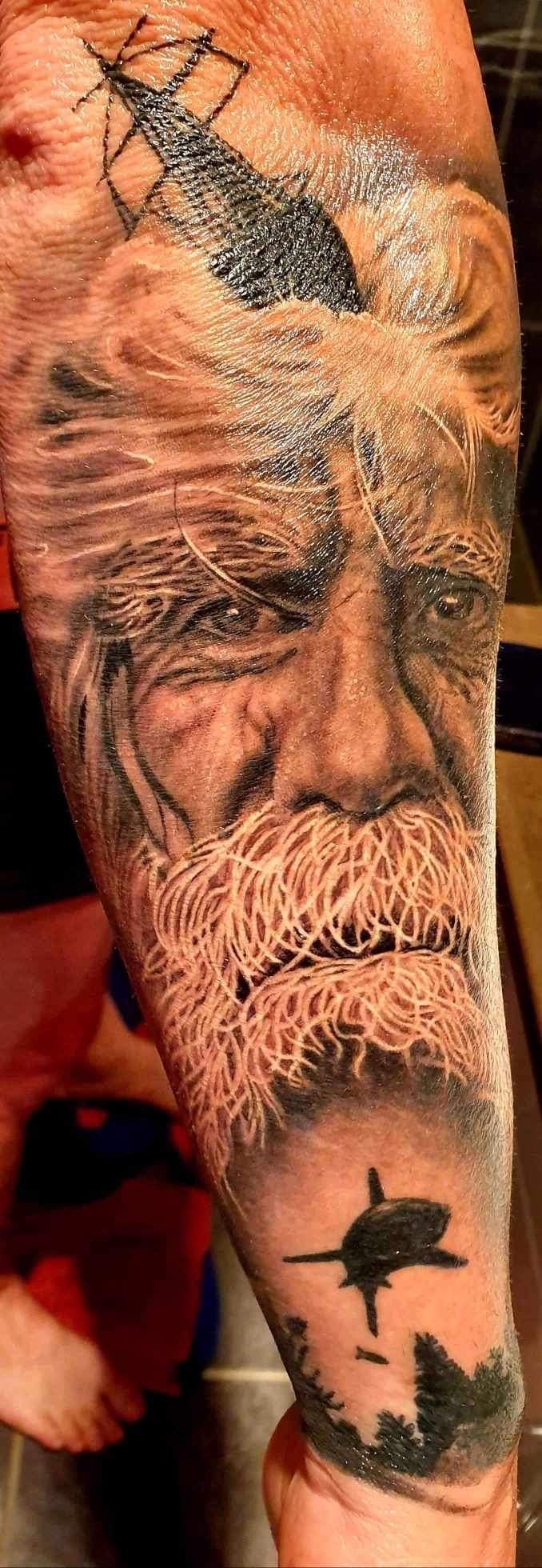 Detailed arm tattoo of an old man with a beard, a black object, and a stylized plane. — Whitsunday Tattooing Airlie Beach in Whitsundays, QLD