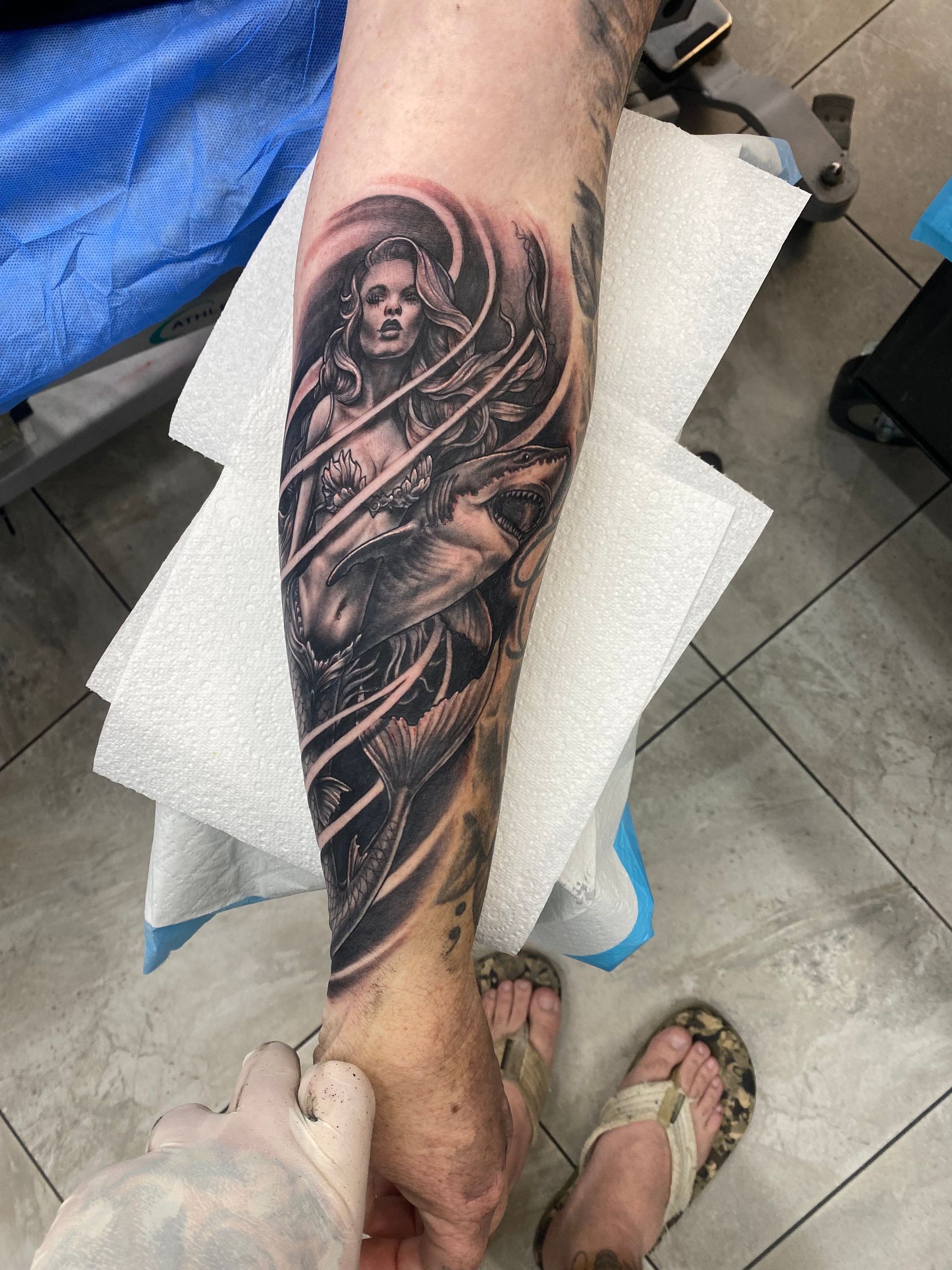 Tattoo of a woman on a person's lower leg. Black and white shading. Person's hand and foot also visible. — Whitsunday Tattooing Airlie Beach in Whitsundays, QLD