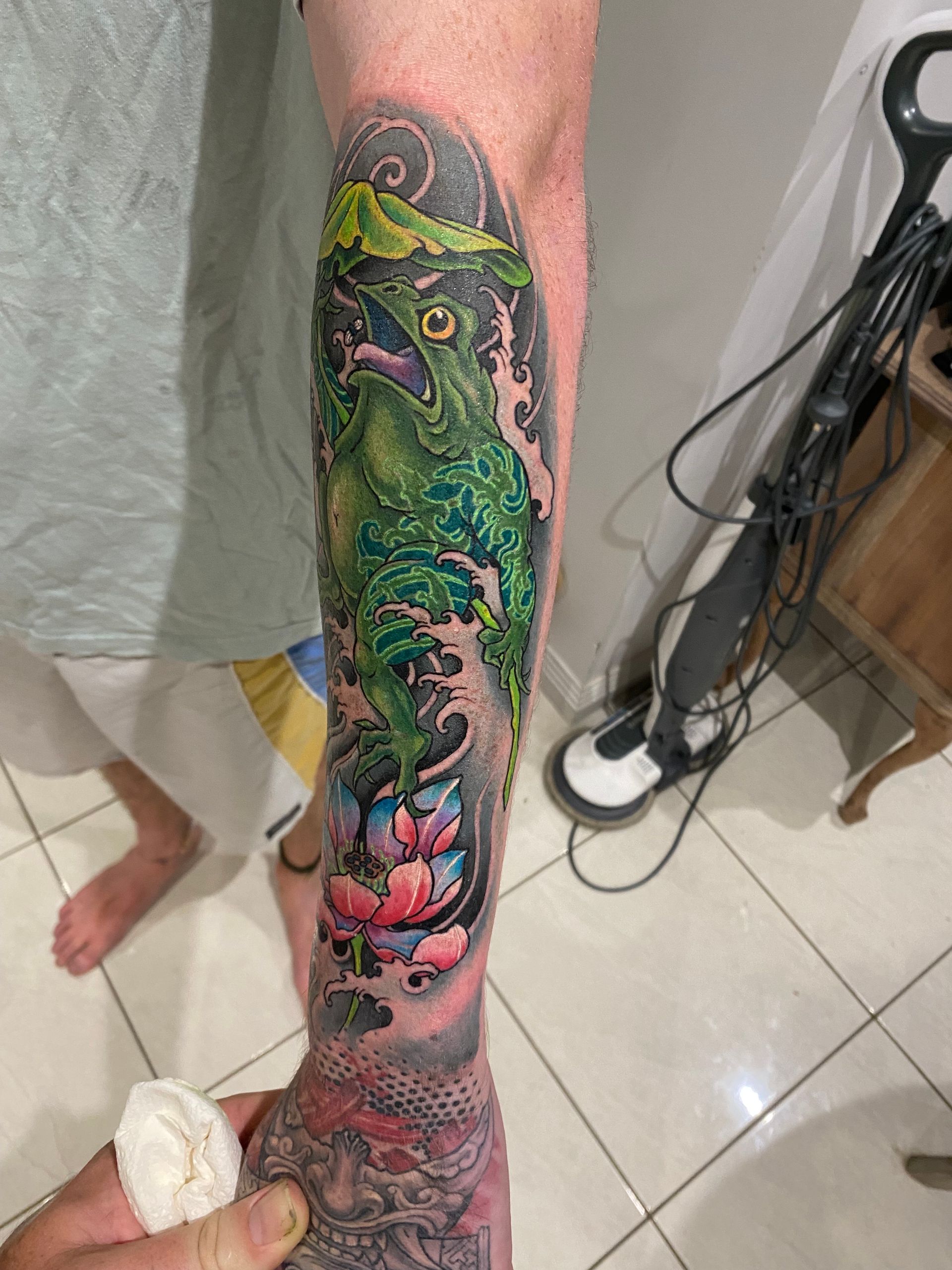 Green lizard tattoo on forearm with water and lotus flowers. — Whitsunday Tattooing Airlie Beach in Whitsundays, QLD