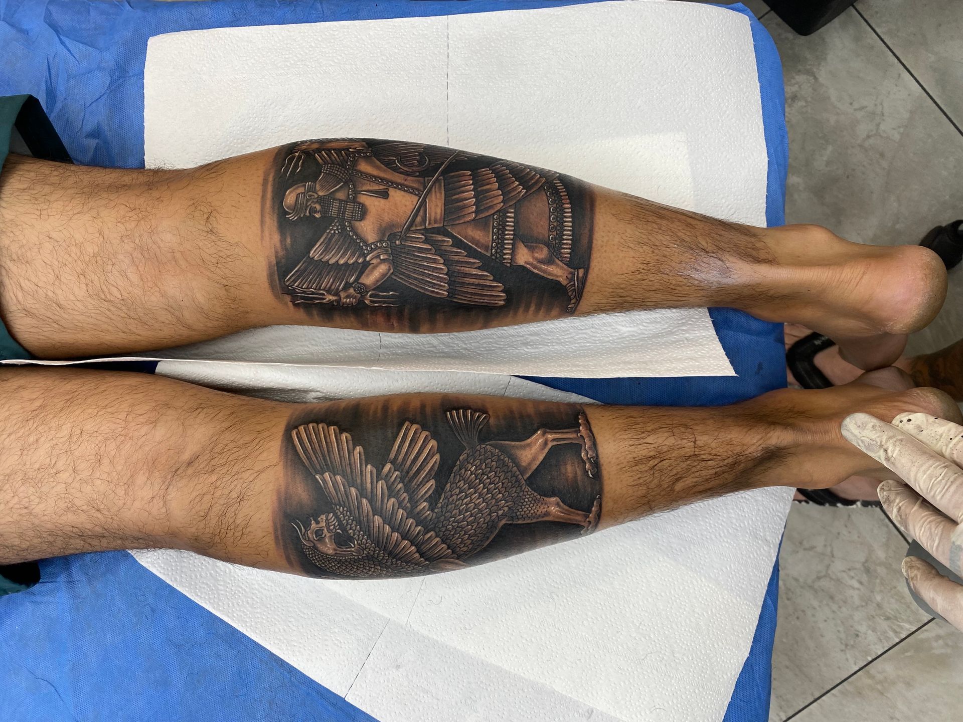Two legs with matching black and grey tattoos of an owl and an image of a person. — Whitsunday Tattooing Airlie Beach in Whitsundays, QLD