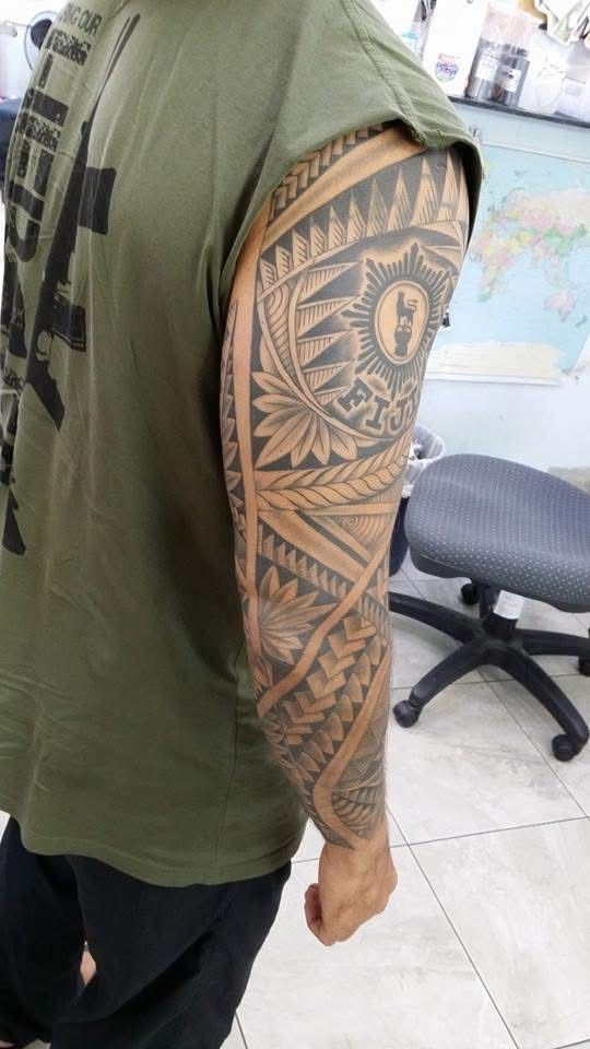 Man with dark tribal sleeve tattoo, wearing an olive green shirt. — Whitsunday Tattooing Airlie Beach in Whitsundays, QLD
