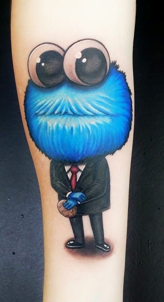 Cookie Monster tattoo in a suit with large eyes, holding a cookie. Blue, black, and red colors. — Whitsunday Tattooing Airlie Beach in Whitsundays, QLD