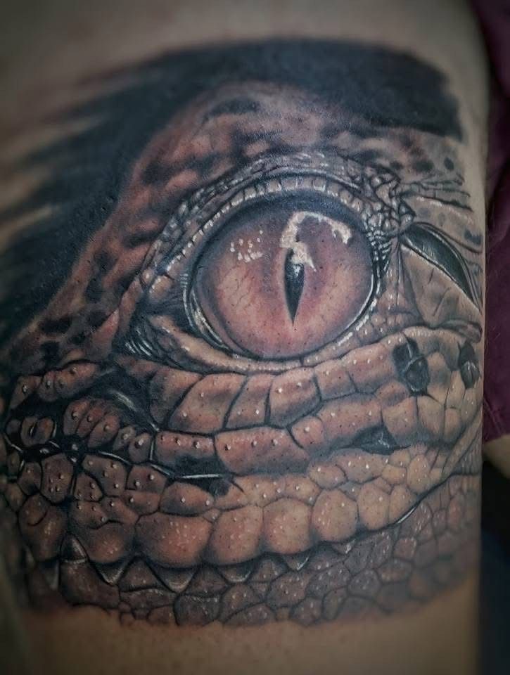Close-up of a detailed crocodile eye tattoo. Brown scales and a reddish-brown eye with reflection. — Whitsunday Tattooing Airlie Beach in Whitsundays, QLD