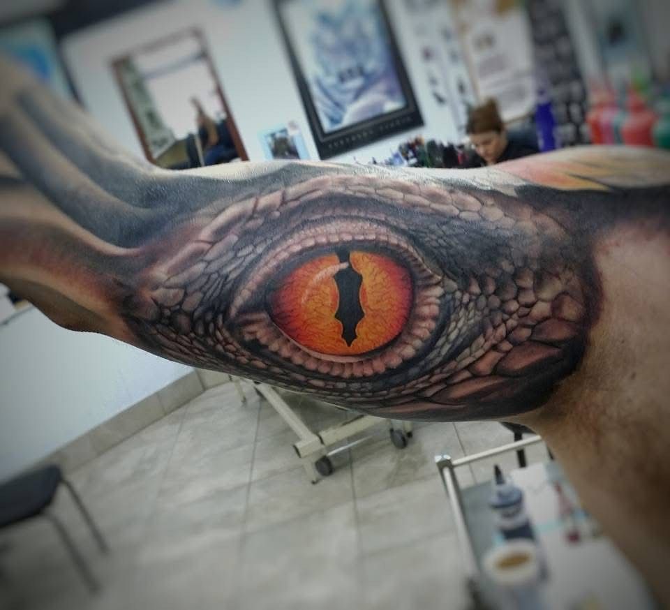 Realistic reptile eye tattoo on arm, orange and black with textured skin detail. — Whitsunday Tattooing Airlie Beach in Whitsundays, QLD
