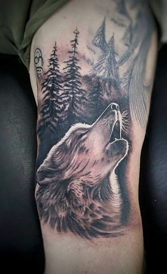 Black and white tattoo of a howling wolf against a backdrop of trees, on an arm. — Whitsunday Tattooing Airlie Beach in Whitsundays, QLD