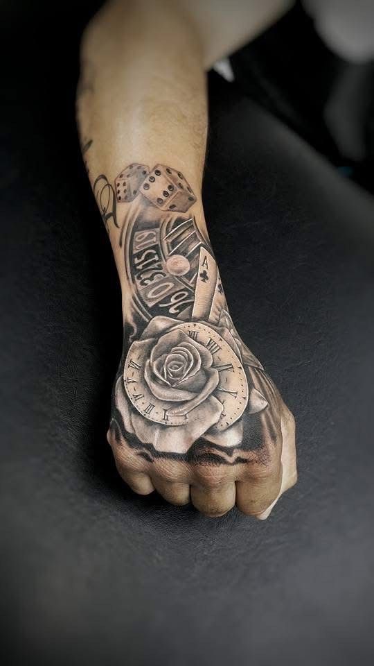 Close-up of a hand with a black and gray rose tattoo on the knuckles and a clock and playing cards on the wrist. — Whitsunday Tattooing Airlie Beach in Whitsundays, QLD