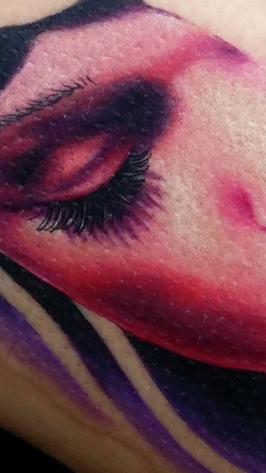 Close-up of a tattoo: a woman's closed eye, long eyelashes, and shaded face in purple and pink. — Whitsunday Tattooing Airlie Beach in Whitsundays, QLD