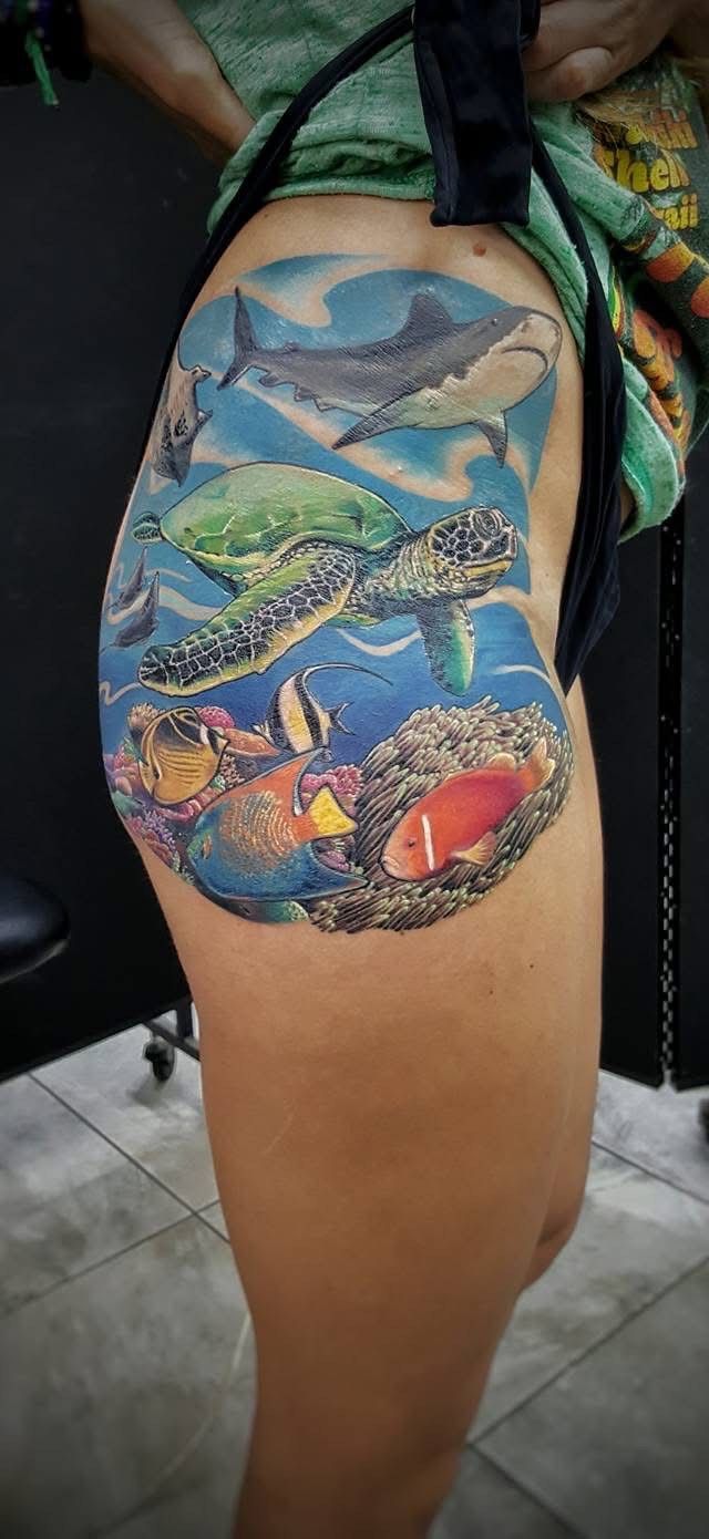 A vibrant aquatic tattoo on a leg. Depicts a sea turtle, fish, coral reef, and a marlin in shades of blue and color. — Whitsunday Tattooing Airlie Beach in Whitsundays, QLD