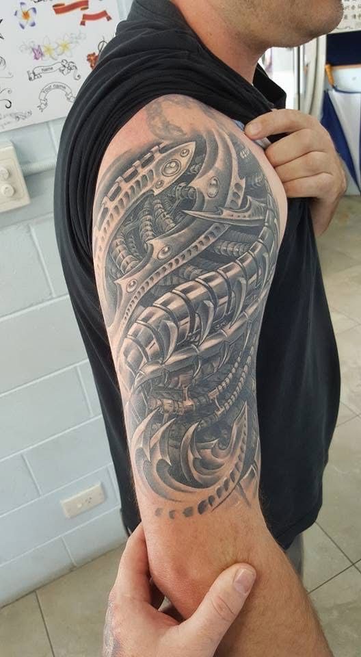 Man's arm with a detailed biomechanical tattoo in shades of gray, showcasing gears and intricate designs. — Whitsunday Tattooing Airlie Beach in Whitsundays, QLD
