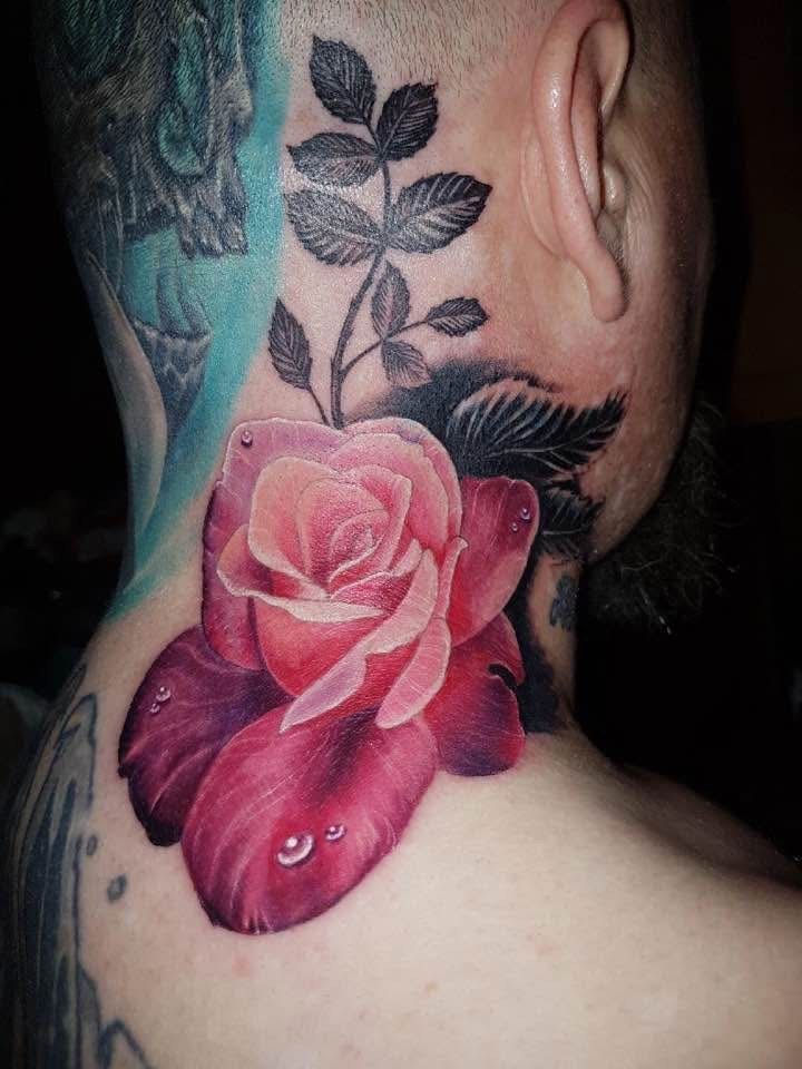 Tattoo of a vibrant pink rose with water droplets and a leafy stem on the back of a neck. — Whitsunday Tattooing Airlie Beach in Whitsundays, QLD