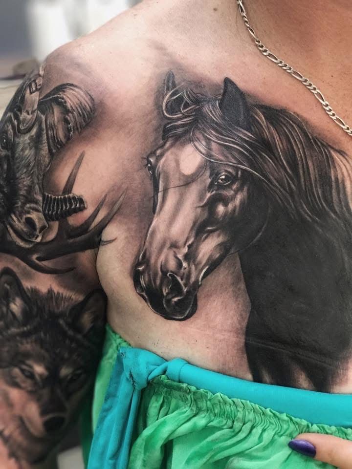 Tattoo of a horse head on a person's chest. Also includes a wolf and elk. Black and white, realistic style. — Whitsunday Tattooing Airlie Beach in Whitsundays, QLD