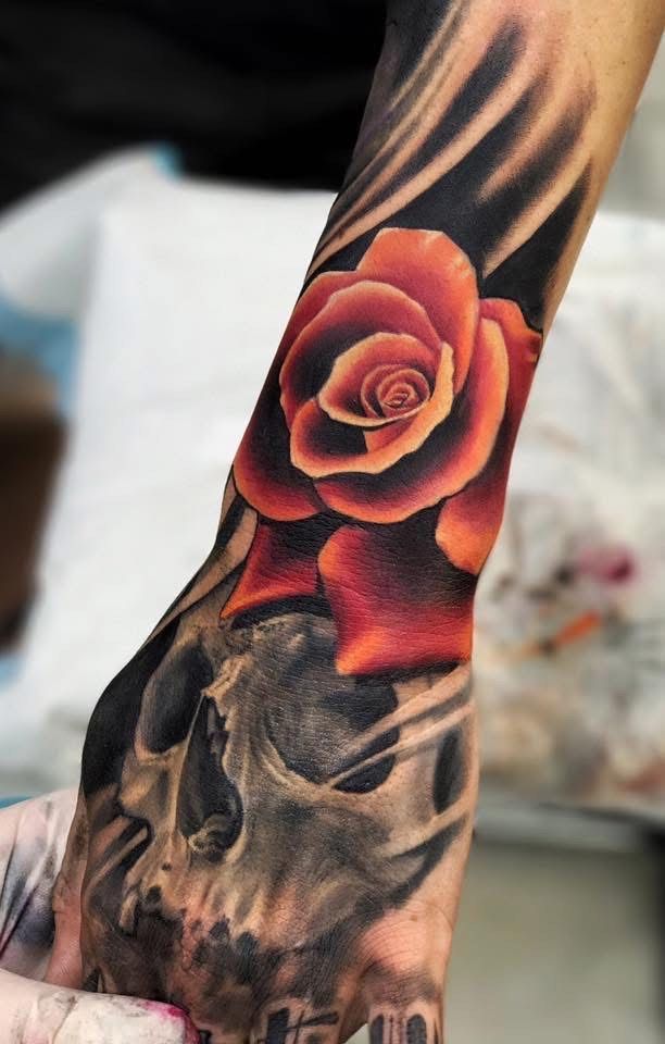 Tattoo of a vibrant red rose over a grayscale skull, with dark shading on a forearm. — Whitsunday Tattooing Airlie Beach in Whitsundays, QLD
