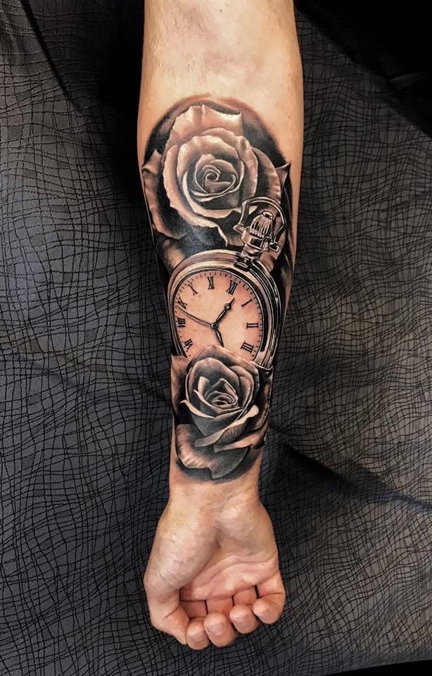 Tattoo of a pocket watch surrounded by roses, on a person's forearm, black and gray shading. — Whitsunday Tattooing Airlie Beach in Whitsundays, QLD