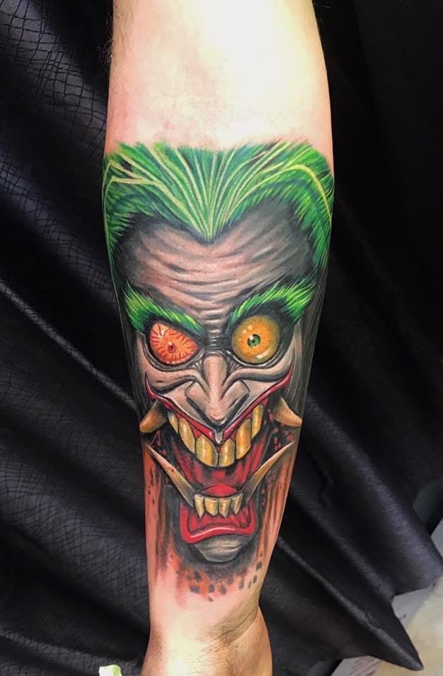 Joker face tattoo with green hair, yellow eyes, wide grin, and detailed shading on arm. — Whitsunday Tattooing Airlie Beach in Whitsundays, QLD