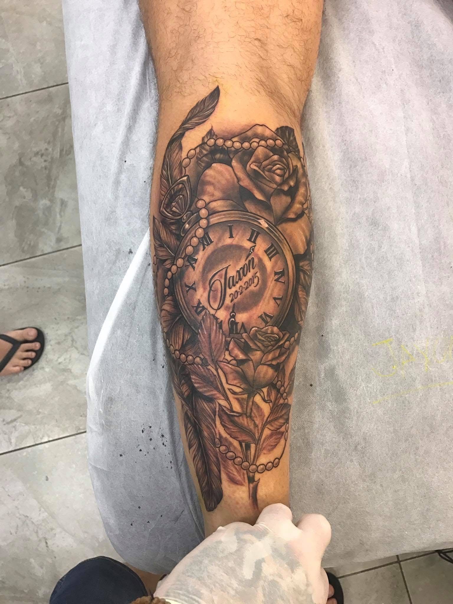 Tattoo of a clock face and rose on an arm. Person wearing gloves is holding the arm. — Whitsunday Tattooing Airlie Beach in Whitsundays, QLD