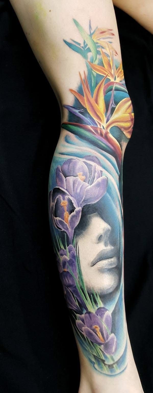 A colorful tattoo on a leg. It features a woman's face surrounded by purple flowers and tropical flowers. — Whitsunday Tattooing Airlie Beach in Whitsundays, QLD