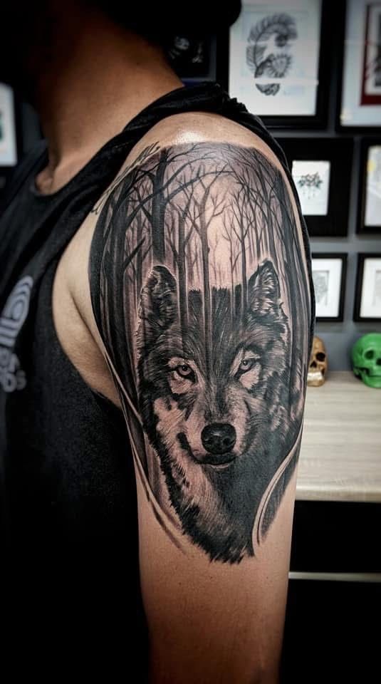 Wolf head tattoo on arm, set in a forest of trees. Black and gray shading. — Whitsunday Tattooing Airlie Beach in Whitsundays, QLD