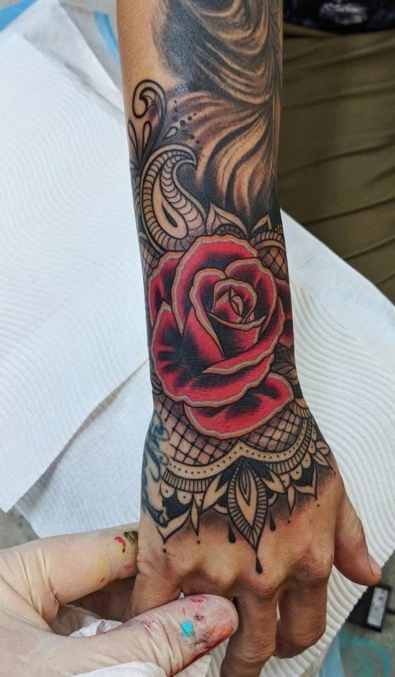 Tattoo of a vibrant red rose and intricate lace design on a wrist and hand. — Whitsunday Tattooing Airlie Beach in Whitsundays, QLD