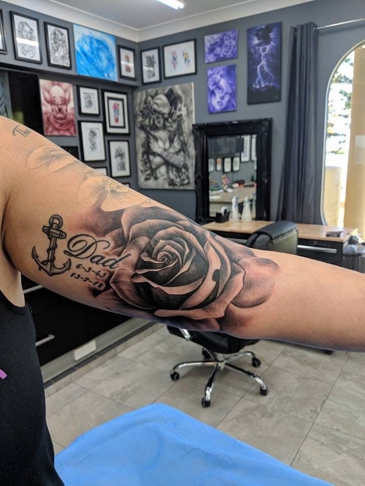 Black and gray rose tattoo on arm, with anchor and